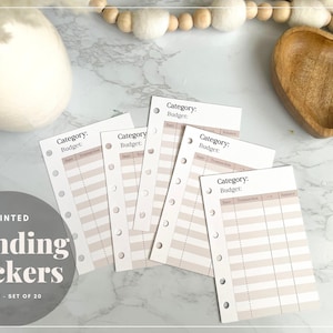 May include: Five white printable spending tracker cards with a light brown background and black text. The cards are labeled "Category: Budget:" and have columns for date, transaction, and balance. The cards are designed for use in a disc-bound planner.