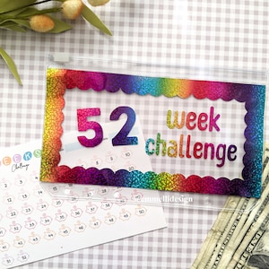 May include: A clear plastic pouch with a rainbow glitter border and the words "52 week challenge." A matching savings tracker is next to the pouch. US dollar bills are visible in the background.