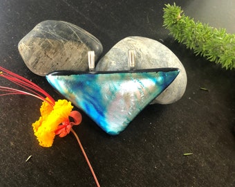 May include: A triangular pendant made of dichroic glass with a blue, green, and iridescent finish. The pendant has silver bail attachments.