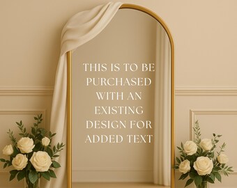 May include: A gold-framed arched mirror with a cream-colored drape. The mirror has the text "THIS IS TO BE PURCHASED WITH AN EXISTING DESIGN FOR ADDED TEXT". Two bouquets of white roses and greenery flank the mirror.