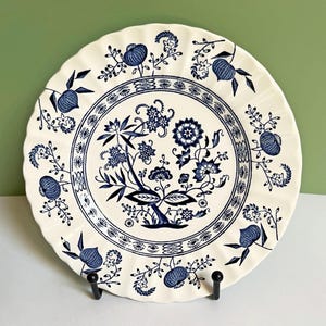 Puede incluir: Un letrero de madera hecho a mano con la palabra "Bienvenido" en una fuente juguetona. El letrero está pintado de blanco con un acabado envejecido y presenta un diseño floral en tonos rosas y verdes. Mide aproximadamente 30 cm de ancho.
