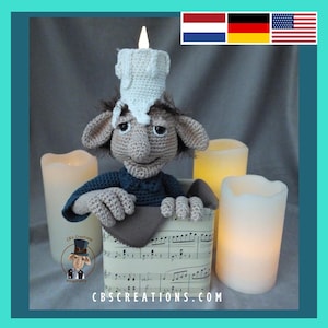 May include: A crocheted gnome wearing a white candle hat, peeking out of a box with sheet music on the side. The gnome is surrounded by white pillar candles.
