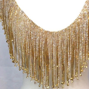 May include: Gold and silver fringe trim with a beaded design. The fringe is made of small, shiny beads that are strung together on a thin wire. The trim is perfect for adding a touch of glamour to any project.