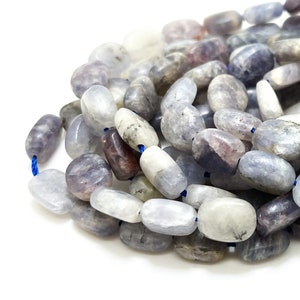 Peut inclure: Un fil de perles de pierres précieuses ovales dans des tons de bleu, gris et blanc. Les perles sont enfilées sur un cordon bleu. Les perles polies varient en taille et ont une surface lisse. Mesure en centimètres.