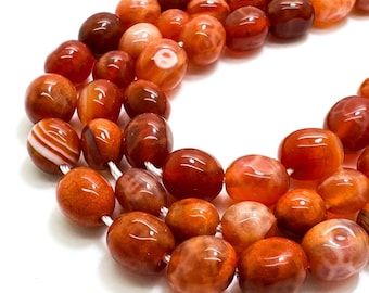 May include: Strands of polished carnelian gemstone beads in shades of orange, red, and brown. The beads are oval-shaped and vary in size, with some displaying natural patterns. Ideal for jewelry making.