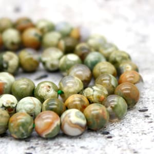 May include: A strand of green, brown, and white agate beads. The beads are round and have a natural, polished finish.