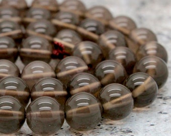 Może przedstawiać: Szereg koralików z dymnego kwarcu, każdy koralik jest okrągły i przeźroczysty w jasnobrązowym kolorze. Koraliki są ułożone w okrągły wzór.
