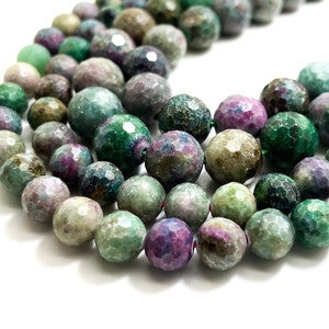 May include: A strand of faceted green, purple, and gray gemstone beads. The beads are round and have a rough, textured surface.