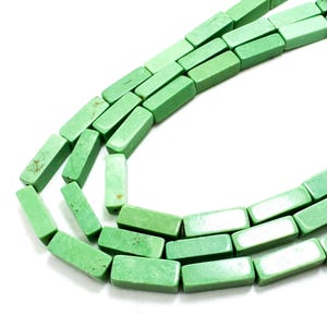 May include: Strands of rectangular, light green beads. The beads are a pale, muted green color and appear to be made of stone or a similar material. The beads are strung together, forming multiple strands against a white background.