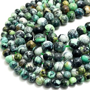May include: Strands of round gemstone beads in shades of green, teal, and gray. The beads have a mottled appearance, with variations in color and texture. The beads are strung together, creating a necklace or bracelet.