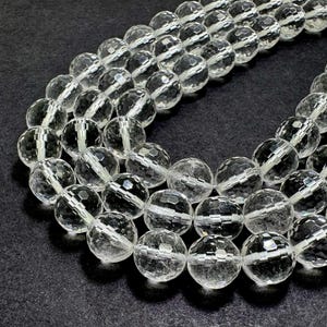 May include: Several strands of clear, faceted crystal beads. The beads are round and have multiple facets that catch the light, creating a sparkling effect. The beads are strung together, forming necklaces or strands for jewelry making.