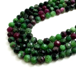 May include: A strand of green and pink gemstone beads. The beads are faceted and have a round shape.