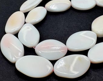 May include: A necklace or bracelet component featuring oval-shaped, polished beads in white and pale pink hues. The beads are strung on a thin, pink string. The background is a dark, solid colour.