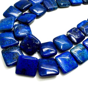 May include: A strand of dark blue lapis lazuli gemstone beads, each bead is square shaped with rounded edges.