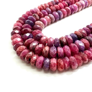 May include: A strand of faceted ruby beads in shades of pink and purple. The beads are round and have a smooth, polished finish.