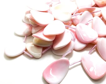 May include: A collection of pink, heart-shaped beads strung on pink thread. The beads have a glossy finish and vary in shades of pink. The beads are scattered on a white surface. The beads are measured in centimetres.