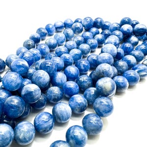 Peut inclure: Un brin de perles de pierres pr&eacute;cieuses bleues et blanches. Les perles sont rondes et ont une finition lisse et polie.