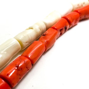 May include: A strand of white and orange beads. The beads are cylindrical and have a smooth, polished finish. The white beads are made of shell and the orange beads are made of coral.