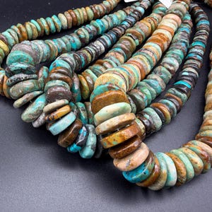 May include: A collection of multi-strand necklaces featuring flat, round, disc-shaped beads in various shades of turquoise, tan, brown, and cream. The beads exhibit natural color variations and textures, arranged in several parallel strands.