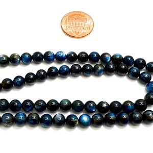 May include: A strand of dark blue and black tiger's eye beads. The beads are round and smooth, and they have a subtle shimmer.
