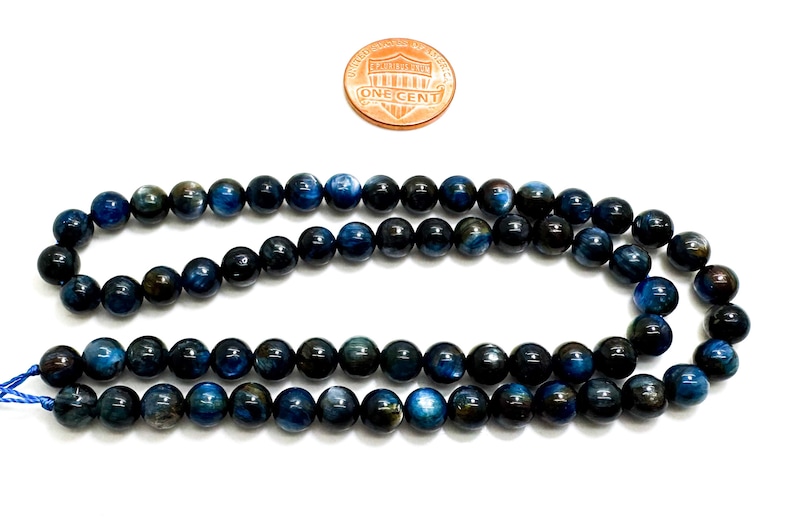 May include: A strand of dark blue and black tiger's eye beads. The beads are round and smooth, and they have a subtle shimmer.