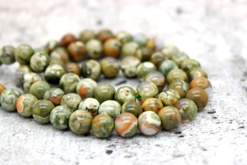 May include: A strand of green, brown, and white agate beads. The beads are round and have a natural, polished finish.