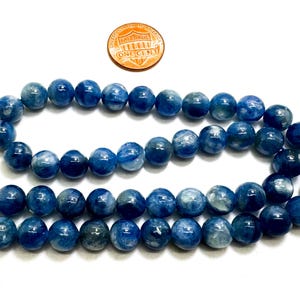 Peut inclure: Un collier de perles de pierres pr&eacute;cieuses bleues et blanches. Les perles sont rondes et ont une finition lisse et polie. Les perles sont enfil&eacute;es sur un cordon fin et blanc.