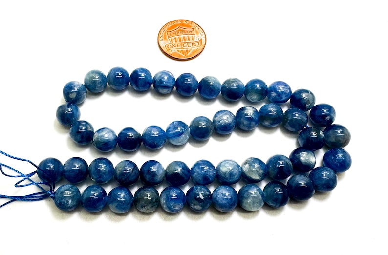 Peut inclure: Un collier de perles de pierres pr&eacute;cieuses bleues et blanches. Les perles sont rondes et ont une finition lisse et polie. Les perles sont enfil&eacute;es sur un cordon fin et blanc.