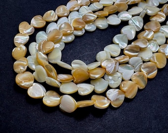 May include: A strand of iridescent heart-shaped shell beads in shades of white and gold. The beads are strung together on a clear thread.