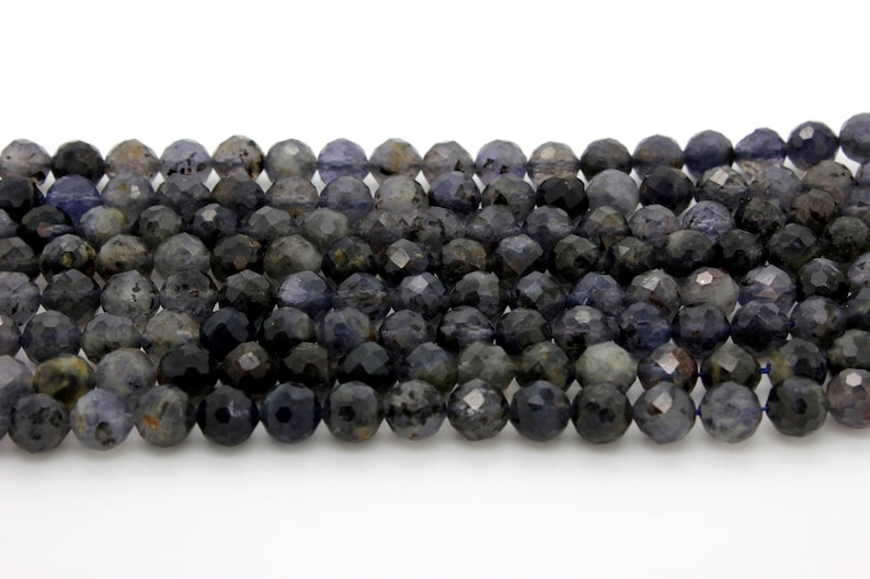 May include: A strand of dark blue faceted gemstone beads. The beads are round and have a slightly iridescent finish.