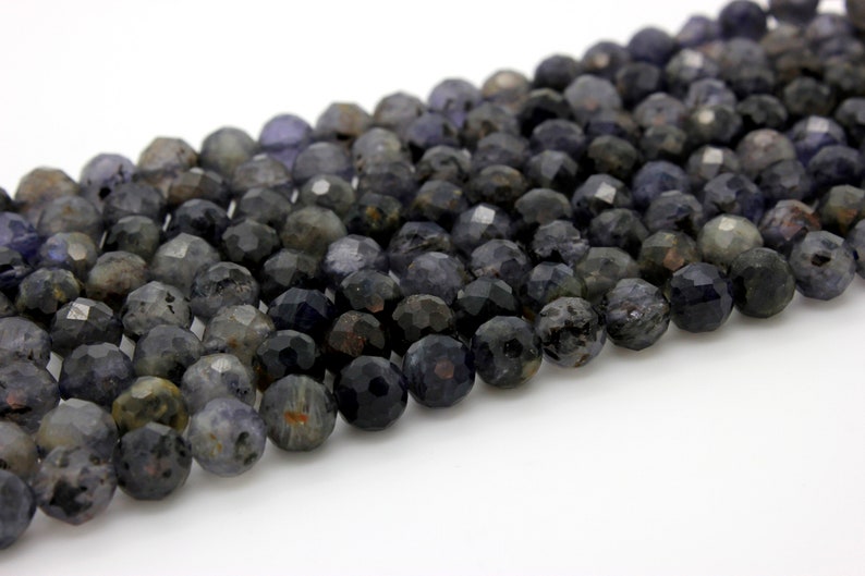 May include: A strand of faceted dark blue and gray gemstone beads. The beads are round and have a slightly irregular shape.
