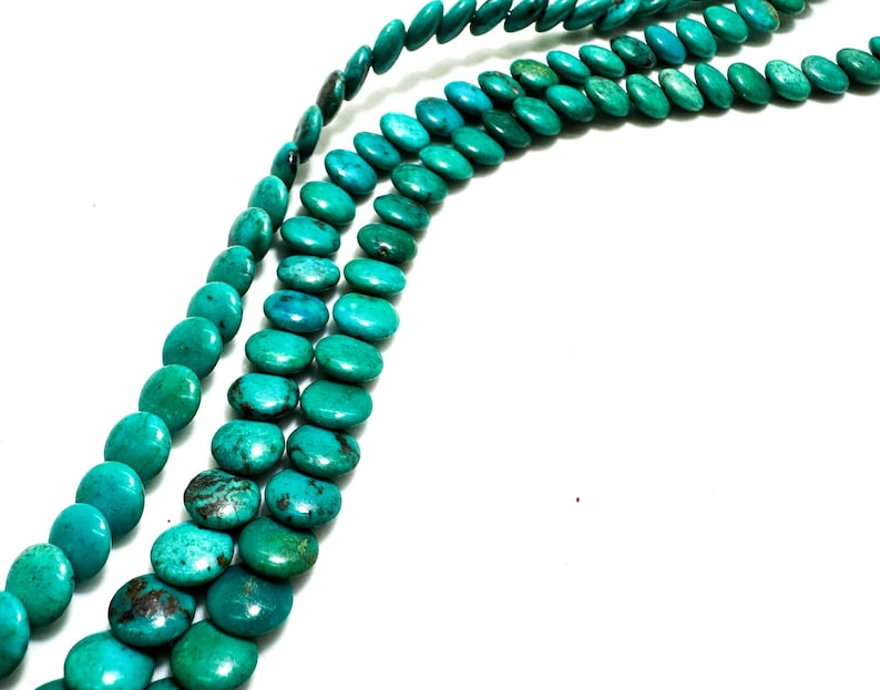 May include: Three strands of turquoise beads, each featuring a flattened, circular coin shape. The beads display a vibrant teal-green color with natural dark brown matrix veining throughout, creating a textured appearance across the strands.