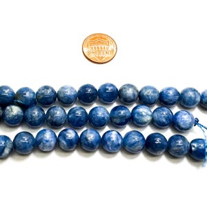 Peut inclure: Un brin de perles de pierre pr&eacute;cieuse bleu ciel, d'environ 10 mm de diam&egrave;tre. Les perles sont rondes et ont une finition lisse et polie. Les perles sont enfil&eacute;es sur un fil bleu fin.