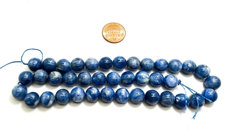 Peut inclure: Un brin de perles de pierre pr&eacute;cieuse bleu ciel, d'environ 10 mm de diam&egrave;tre. Les perles sont rondes et ont une finition lisse et polie. Les perles sont enfil&eacute;es sur un fil bleu fin.