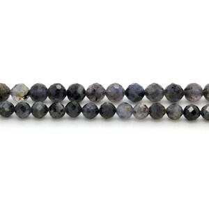 May include: A strand of dark blue faceted gemstone beads. The beads are round and have a slightly irregular shape.