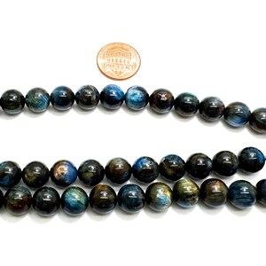 May include: A strand of blue tiger's eye beads, approximately 8mm in diameter. The beads have a dark blue base with golden brown streaks and a slight shimmer.