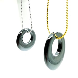May include: Two necklaces with black hematite donut pendants. One necklace has a silver chain and the other has a gold chain.