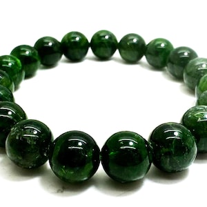 May include: A green gemstone bracelet with round beads. The beads are a deep green colour with a slightly translucent quality.