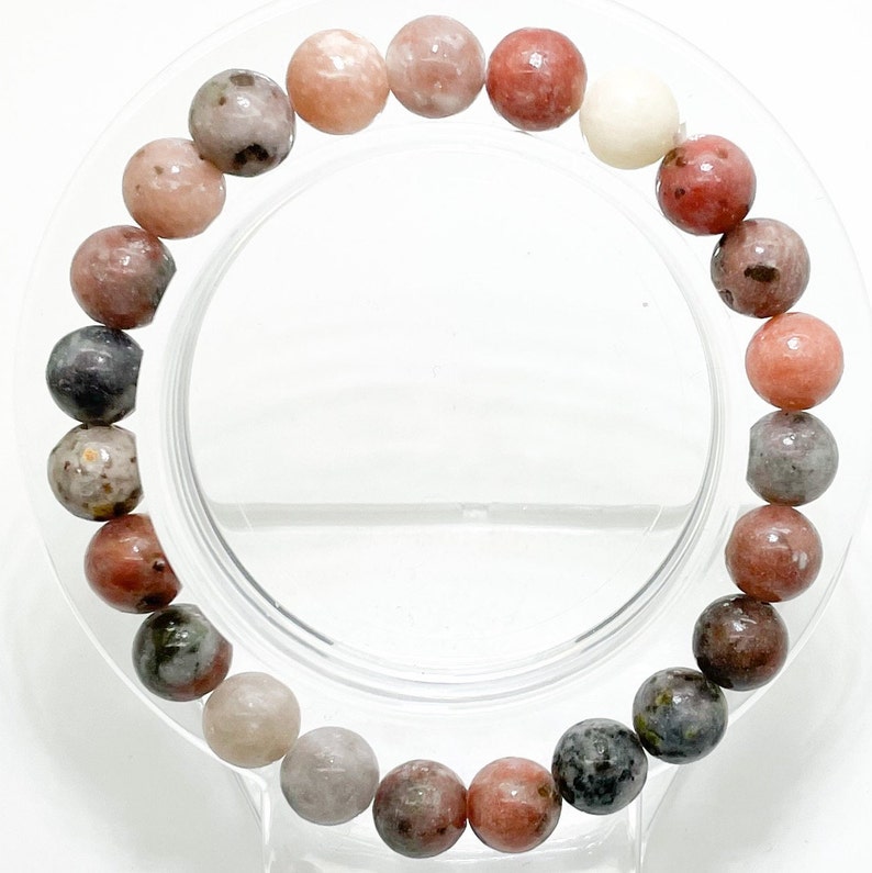 May include: A pink, grey, and white gemstone bracelet with round beads. The bracelet is made of natural stones and is approximately 18 cm in length.