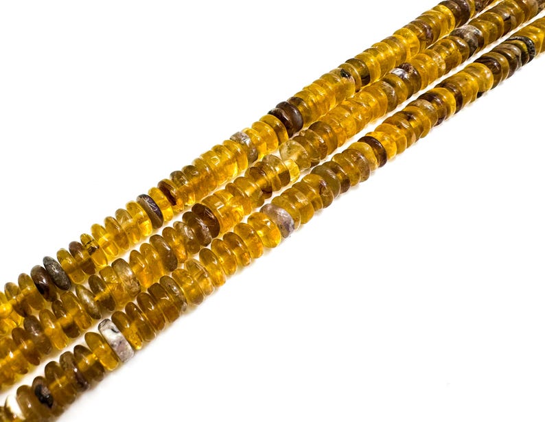 May include: Close-up of three strands of amber-colored gemstone beads. The beads are small, round, and have a slightly irregular shape. The color varies from a light yellow to a deeper, richer amber. The beads are strung together, creating a textured and visually appealing pattern.