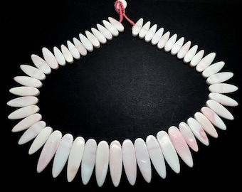 May include: A necklace made of white and pink shell beads in a teardrop shape. The beads are strung on a red cord.