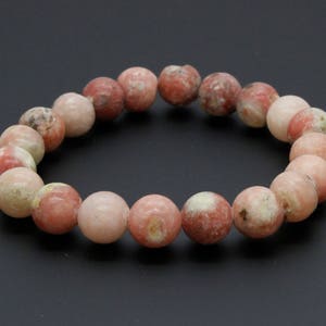 May include: A pink and white gemstone bracelet with round beads. The bracelet is made of natural stones and has a simple design.