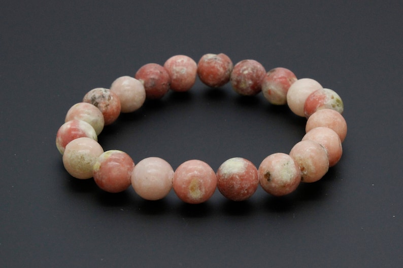 May include: A pink and white gemstone bracelet with round beads. The bracelet is made of natural stones and has a simple design.