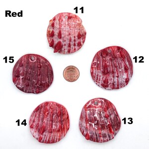 May include: Five red, textured shell pendants with drilled holes for jewelry making. The shells vary in shape and size, with a penny for scale. The word "Red" is in the upper left corner, and numbers 11-15 are next to each shell.