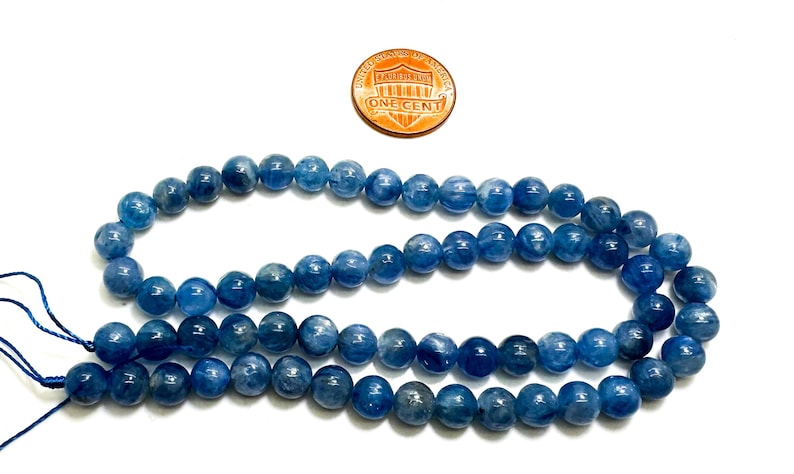 Peut inclure: Un brin de perles d'apatite bleue, d'environ 8 mm de diam&egrave;tre, avec un penny pour comparaison de taille.