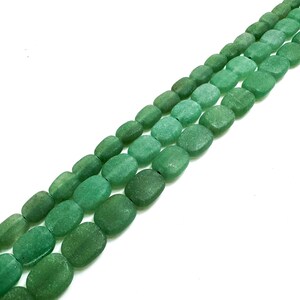 Puede incluir: Tres hilos de cuentas de piedra preciosa de aventurina verde en diferentes tonos. Las cuentas ovaladas tienen una superficie texturizada. Ideal para la creaci&oacute;n de joyas. El fondo es blanco. Las cuentas se miden en cent&iacute;metros.