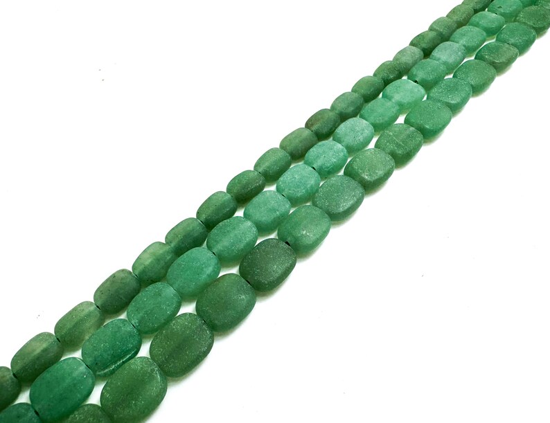 Puede incluir: Tres hilos de cuentas de piedra preciosa de aventurina verde en diferentes tonos. Las cuentas ovaladas tienen una superficie texturizada. Ideal para la creaci&oacute;n de joyas. El fondo es blanco. Las cuentas se miden en cent&iacute;metros.