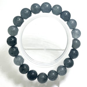 May include: A gray gemstone bracelet with round beads. The bracelet is made of natural stones and is approximately 8 inches in length.