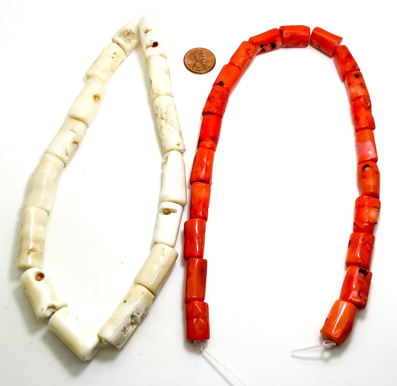 May include: Two strands of coral beads, one white and one orange. The beads are cylindrical and have a rough, natural texture.