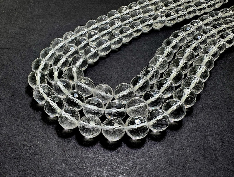 May include: Several strands of clear, faceted crystal beads. The beads are round and have multiple facets that catch the light, creating a sparkling effect. The beads are strung together, forming necklaces or strands for jewelry making.
